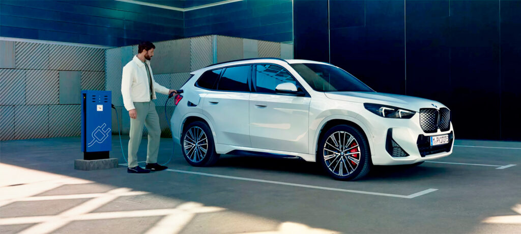 Vediamo un uomo che ricarica una BMW iX1 eDrive20 a una colonnina.